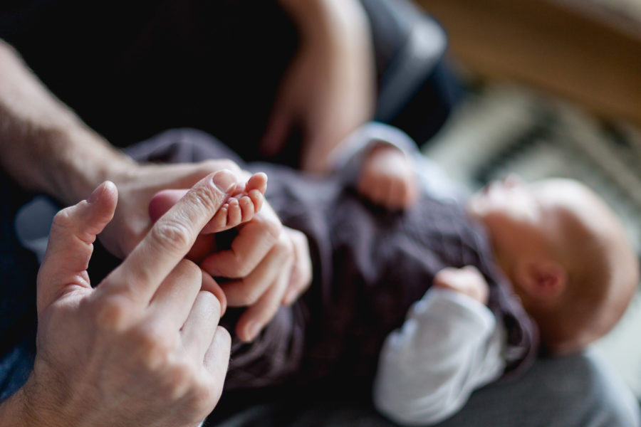 winziges Babyfüßchen wird von Papas Hand sanft gestreichelt