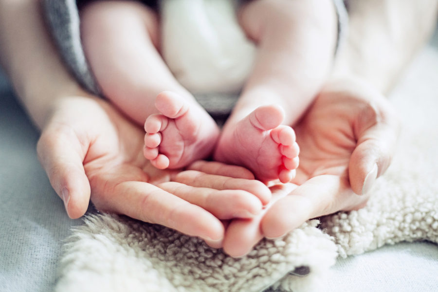 winzige Babyfüße werden von Papas großen Händen gehalten