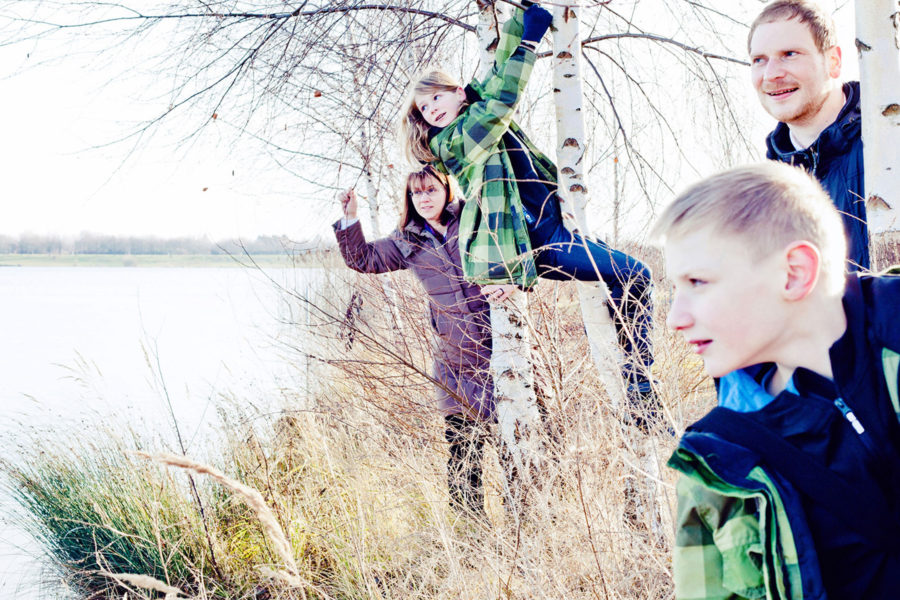 Familie steht zwischen Birken am Kulkwitzer See in Leipzig und genießt die Aussicht