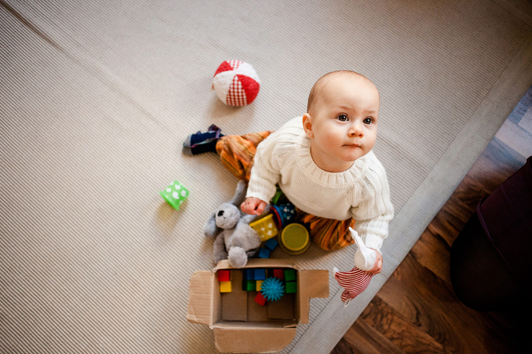 kleines Kind sitzt mit seinen Spielsachen auf dem Boden