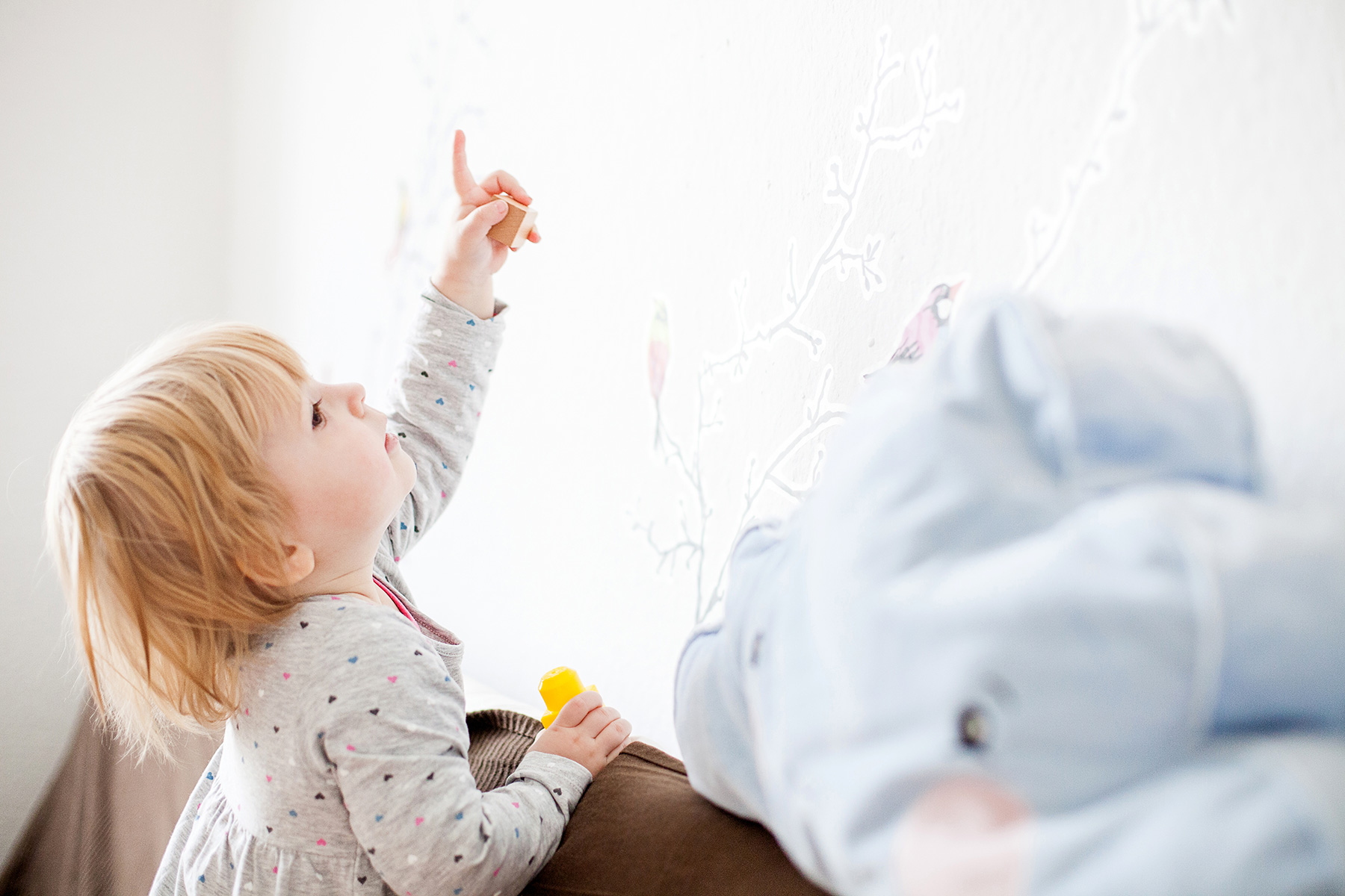 kleines Mädchen zeigt in seinem Kinderzimmer auf ein Wandbild