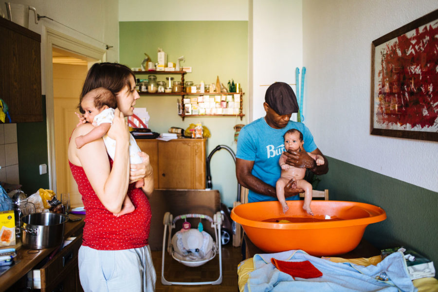 Familie mit Zwillingen beim Babybaden in der Küche
