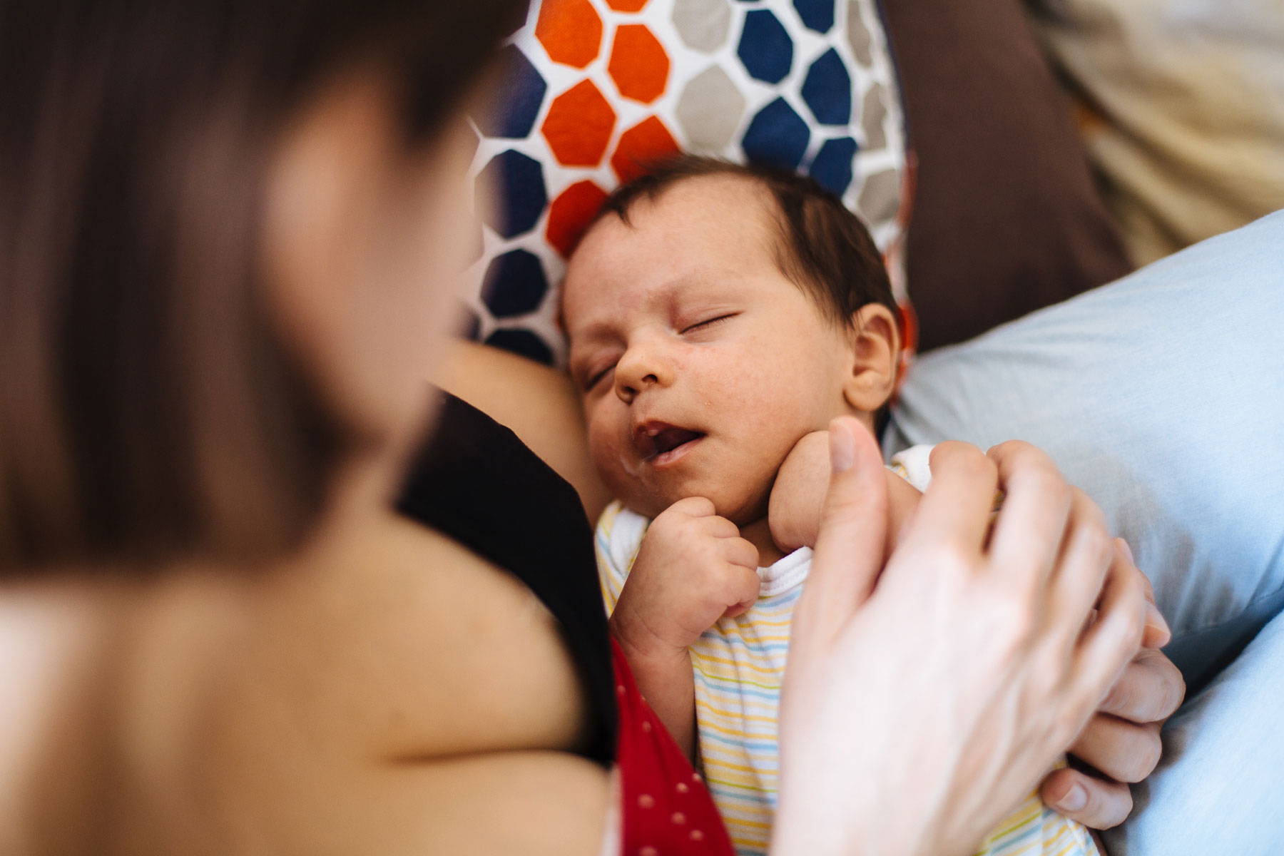 Baby schläft nach Stillmahlzeit auf Mamas Schoß ein